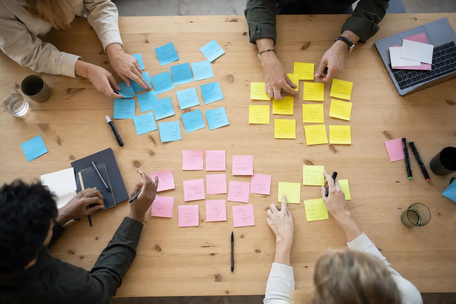 Händer som sorterar färgglada post-it-lappar under en OKR-planering i team